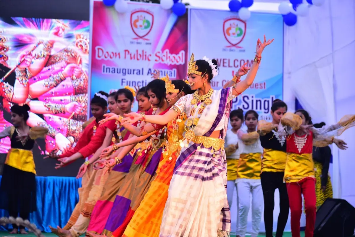 Students in colourful costumes performing a dance on stage at the annual function